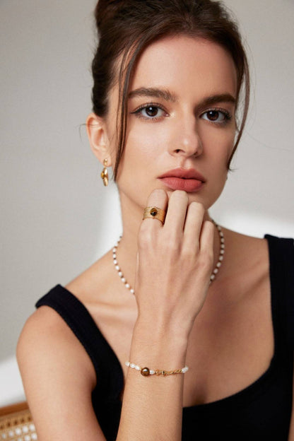 a woman in a black dress is wearing a pearl bracelet