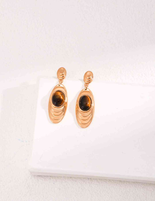 a pair of gold earrings with a tiger's eye
