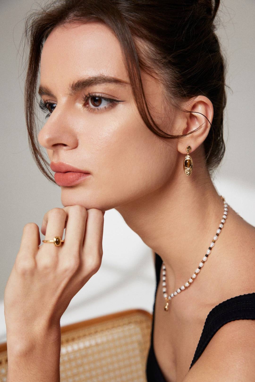 a woman in a black dress wearing a necklace and earrings