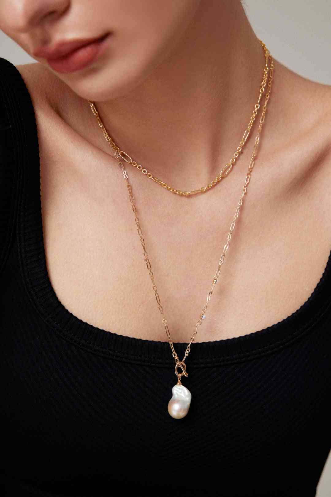 Woman wearing baroque pearl necklace on gold chain