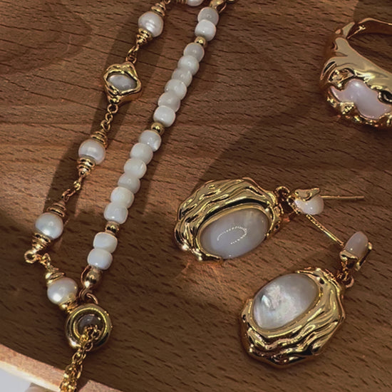 Close-up of seashell bracelet and earrings on wood tray